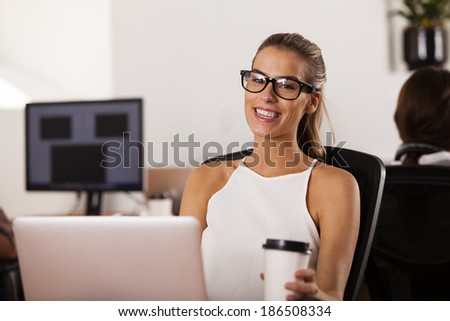 Young woman entrepreneur sitting at her computer and smiling in her startup office