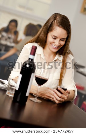 Beautiful young woman checking her smartphone in a restaurant