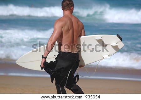 A surfer walks the beach looking for the right break.