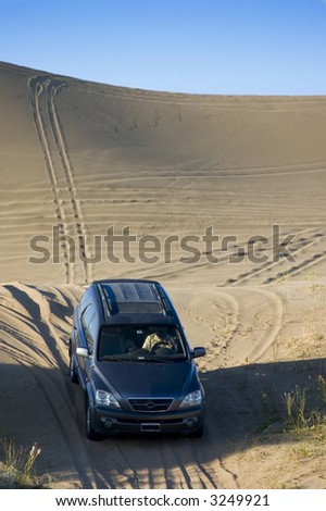 A four-wheel-drive drives through the  sand dunes.