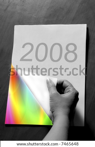 hand turning a 2008 calendar page to reveal a colorful rainbow abstract page