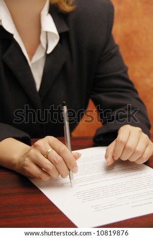 business woman with pen in hand and a contract on the desk