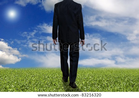a man in suit walking in a meadow, toward a bright future