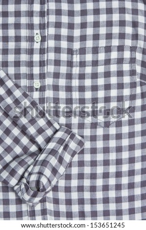 Front of a gingham shirt with a rolled up sleeve