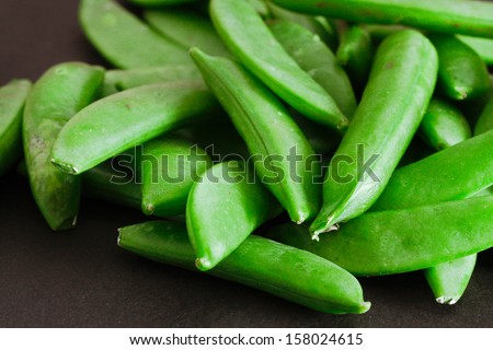 Close up of raw sugar snap peas on a black background