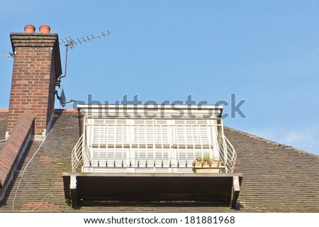 A white metal balcony on the roof of a house