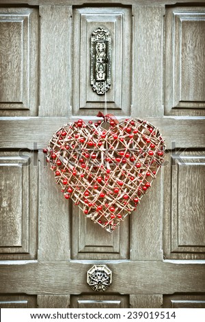 A heart shaped christmas wreath on a wooden front door