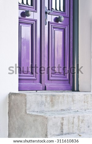 A purple front door of a home with concrete steps