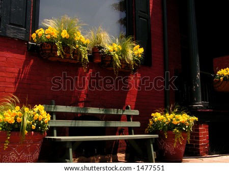 window-box garden of yellow flowers with a bench seat against red brick