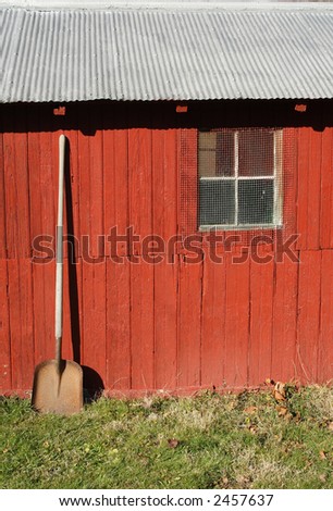 old shovel leaning against bright red tool shed