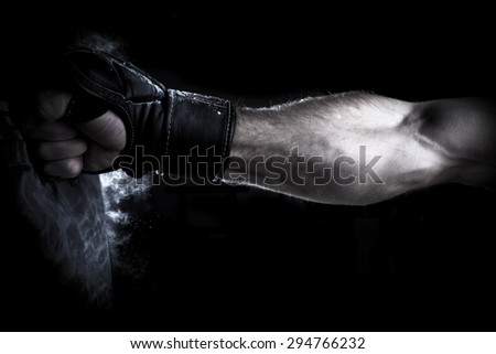 Male Athlete boxer punching a punching bag with dramatic edgy lighting in a dark studio