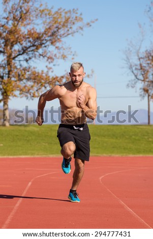 Male Athelete sprinting on a tartan athletics track on a bright sunny day