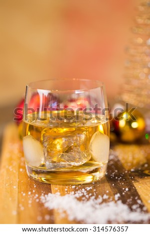 Lovely close up image of Christmas cookies on a wooden chopping board with some scented candles and a glass of whiskey / coffee and some cinnamon sticks.