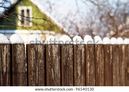 Old wooden fence covered with snow
