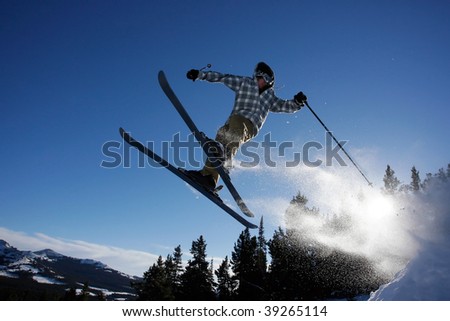 A young man flies through the air after hitting a ski jump in the back country.