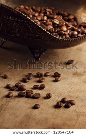coffee beans on a wood in a bronze bowl