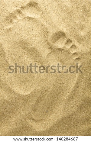 Two footprints in sand at the beach