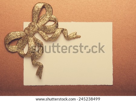 Blank gift tag tied with a gold bow on gold paper