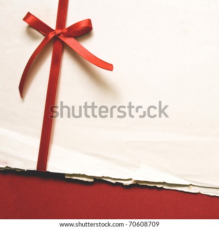 Red gift bow with ribbons and blank old paper on red paper