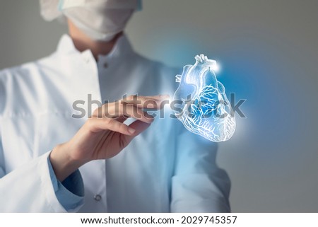 Female doctor touchstone virtual Heart in hand. Blurred photo, handrawn human organ, highlighted blue as symbol of recovery. Healthcare hospital service concept stock photo