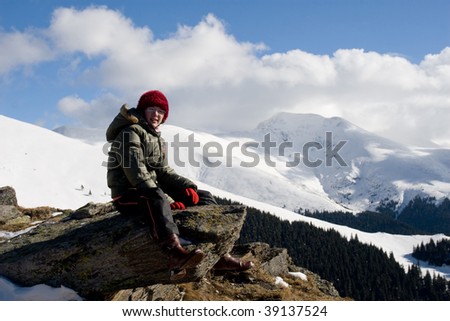 Young girl relaxing in the winter sun near mountain peaks