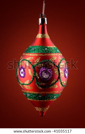 Colorful christmas globe painted with sparkly colors over red background
