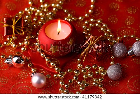 Red christmas background with burning candle, golden pearls, gift boxes and silver globes