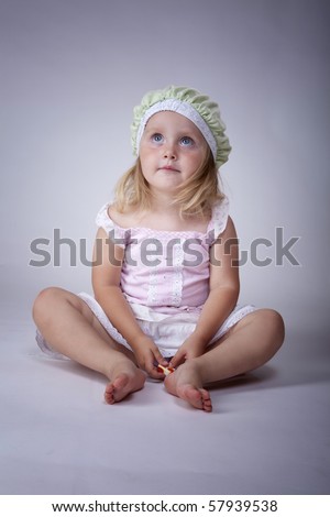 Little girl sitting on the floor with a cute green hat