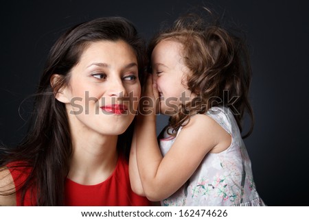 Little girls whispers secretly in mother ears