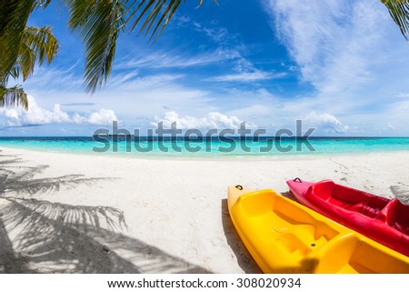 yellow and red kayak on the beach under coco palms