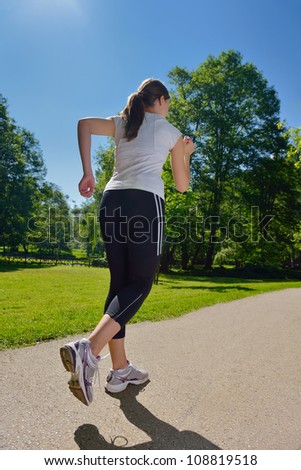 Young beautiful  woman jogging in summer park. Woman in sport outdoors health concept
