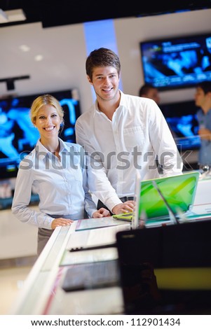 people in consumer electronics  retail store looking at latest laptop, television and photo camera to buy
