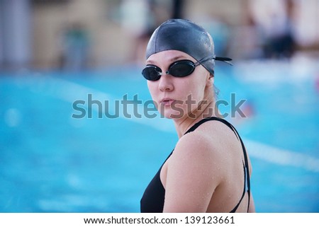 Happy muscular swimming woman  wearing glasses and cap at swim pool and represent health and fit concept