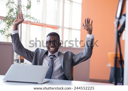 Happy smiling successful African American businessman  in a suit in a modern bright office indoors