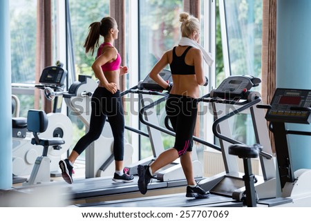 Beautiful group of young women friends  exercising on a treadmill at the bright modern gym