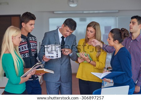 group of students working with teacher on wooden small house model