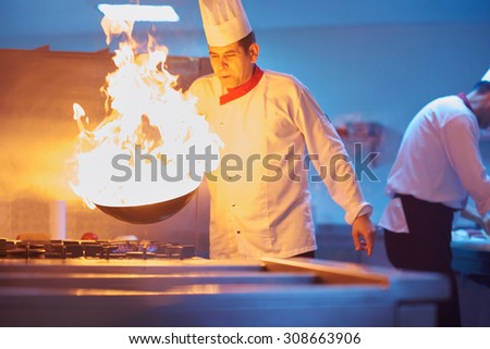 chef in hotel kitchen prepare vegetable  food with fire