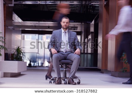 business man sitting in office chair,  people group  passing by: Concept of time, rush, organization
