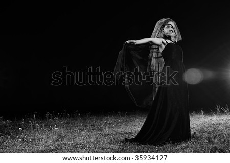 young beautiful bride in black wedding dress in dar at night