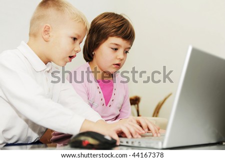 two happy children playing games and learning education lessons on laptop computer at home