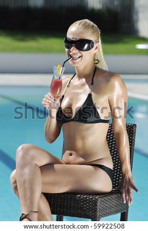young beautiful woman relax drink coctail and have fun with splashing water at hotel swimming pool