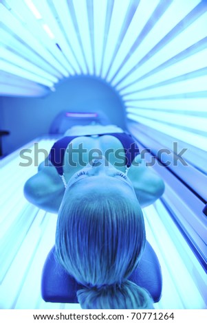 young woman at laying on solarium bed and get brown skin tone ready for summer