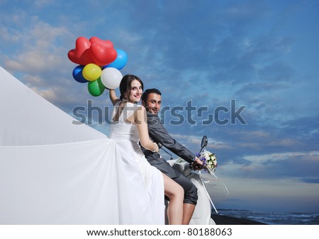 wedding scene of bride and groom just married couple on the beach ride white scooter and have fun