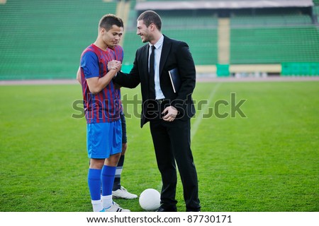 soccer  sport manager in business suit coach and football player on stadium with green grass and white ball