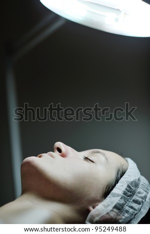 Young beautiful woman receiving cosmetic facial mask in spa beauty salon and relax