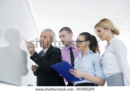 Senior male business man giving a presentation at a  meeting at modern light office on a table board
