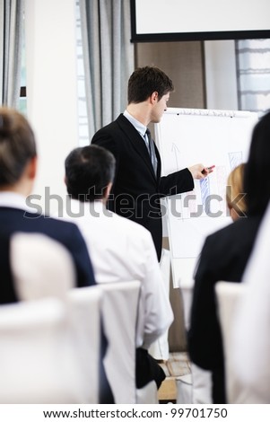 young  male business man giving a presentation at a  meeting seminar at modern conference room  on a table board