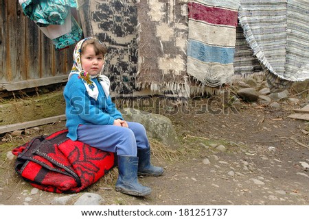 IEUD, ROMANIA - MARCH 20: A child called Maria waiting for her parents while they washing their carpets in a river, before the Easter in Maramures. On March 20, 2007 in Ieud, Romania