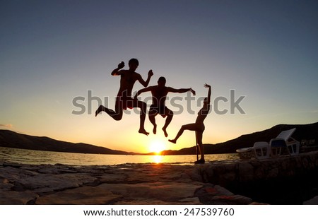 Silhouette of friends jumping at sunset on the beach