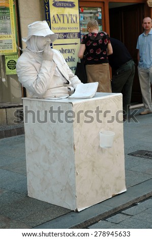 KRAKOW, POLAND - MAY 29: Unmoving street artist plays a writer as a statue. The historical center of Krakow is full with artists and musicians. On May 29, 2005 in Krakow, Poland